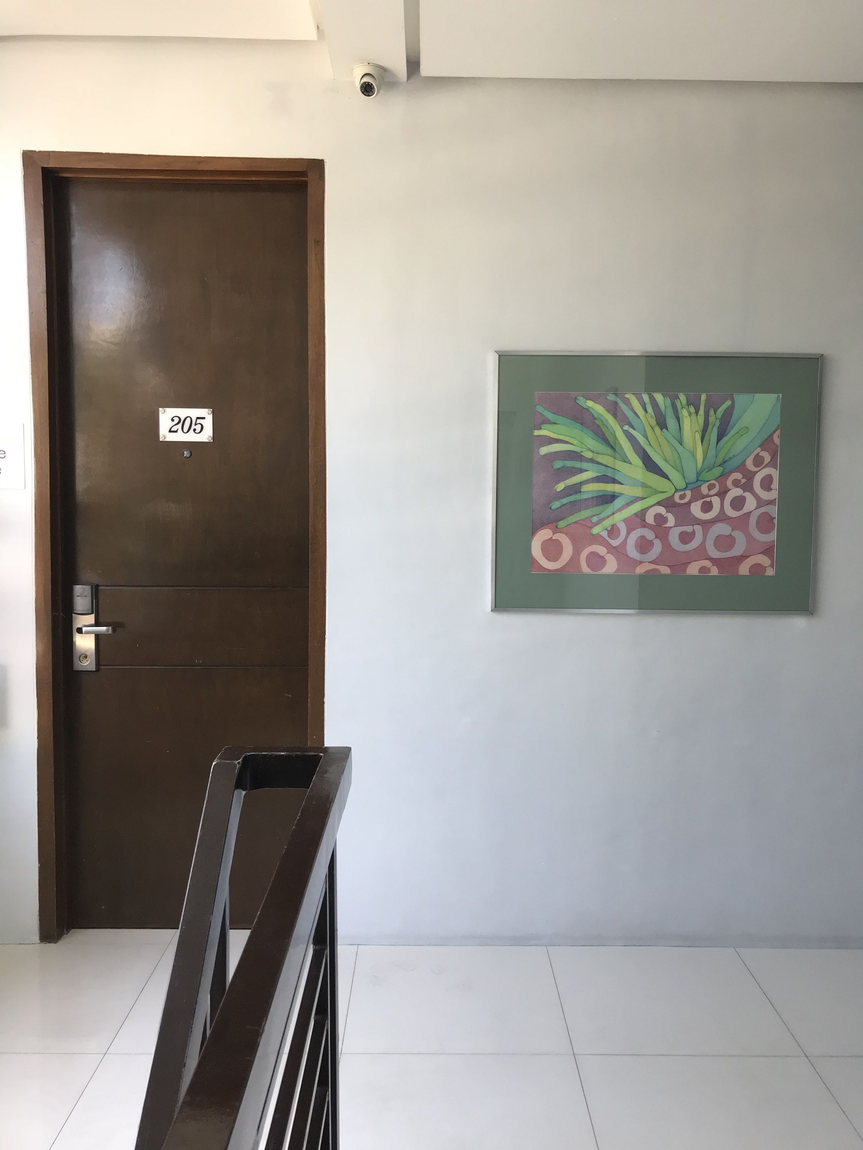 Una puerta con una placa de identificación, una cámara de seguridad y un cuadro en la pared.