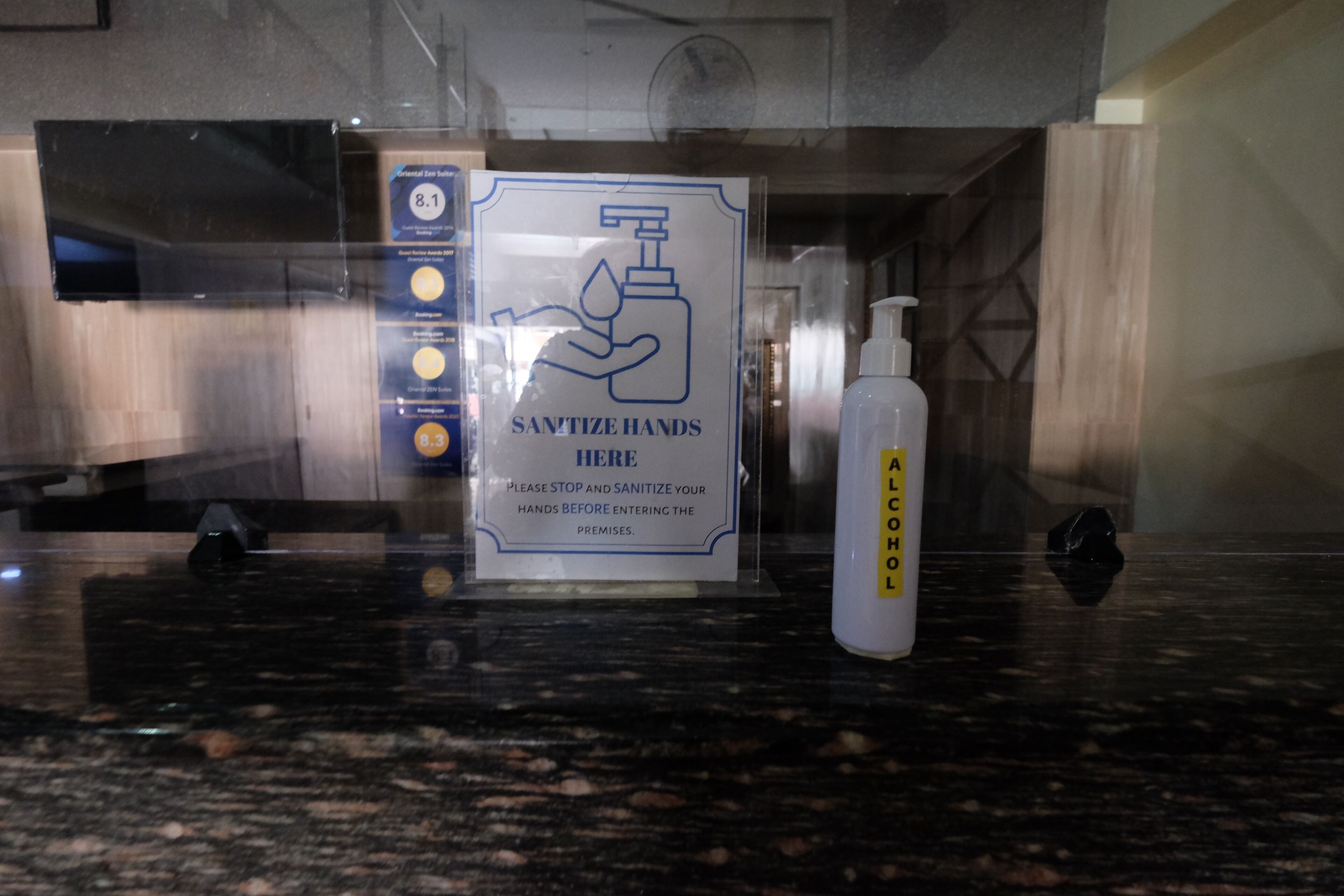 A hand sanitizer dispenser and a sign instructing to sanitize hands before entering the premises.