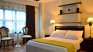 Een hotelkamer met een bed, twee stoelen, een klein tafeltje en een lamp.