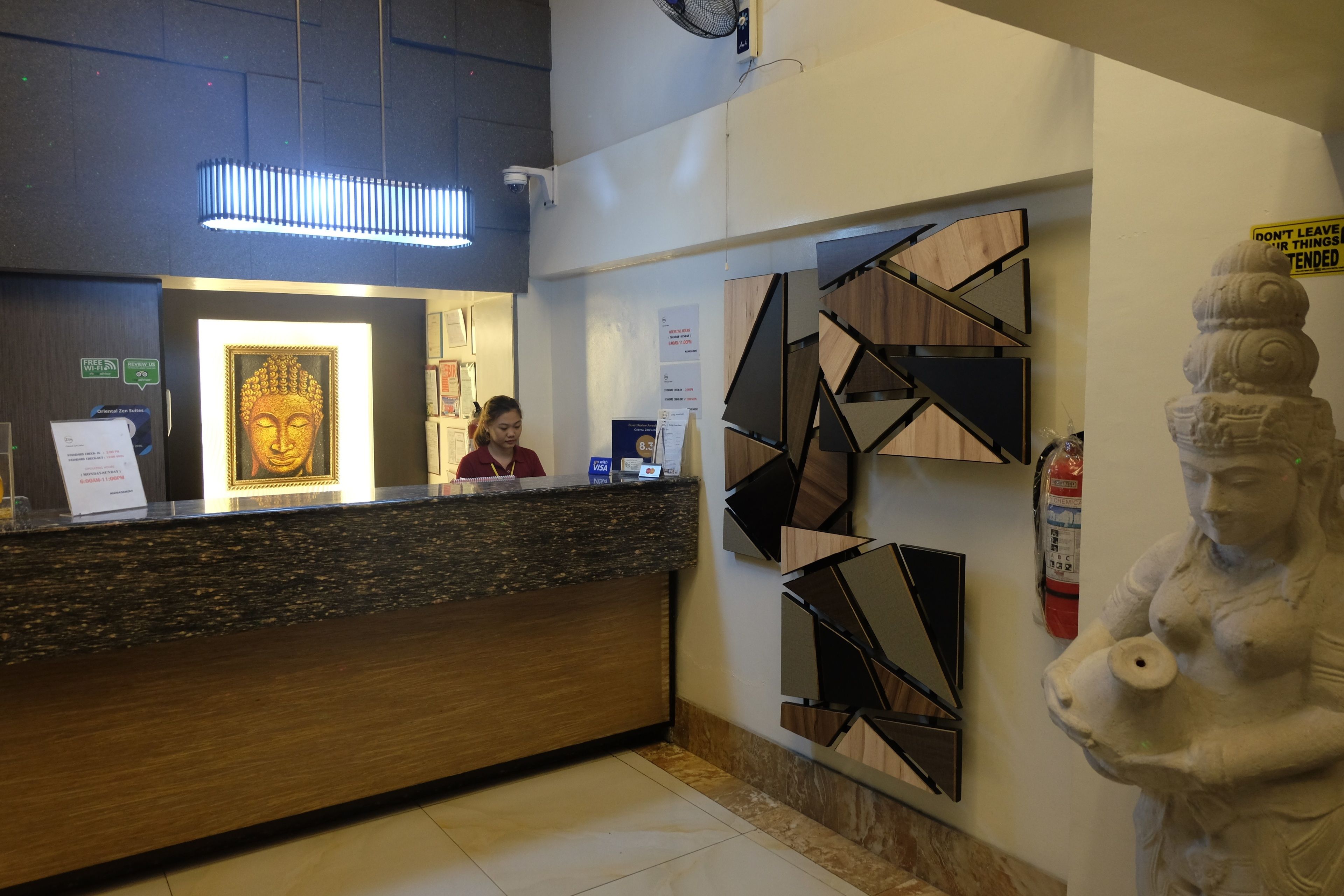Un mostrador de recepción con una estatua de Buda, un extintor y un cartel en la pared.