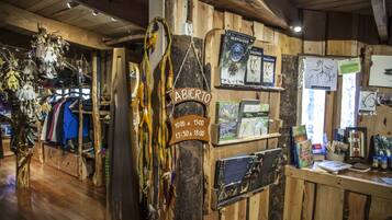 A rustic interior with wooden walls, a sign indicating 'ABICERO' and operating hours, and various items displayed on shelves and counters.