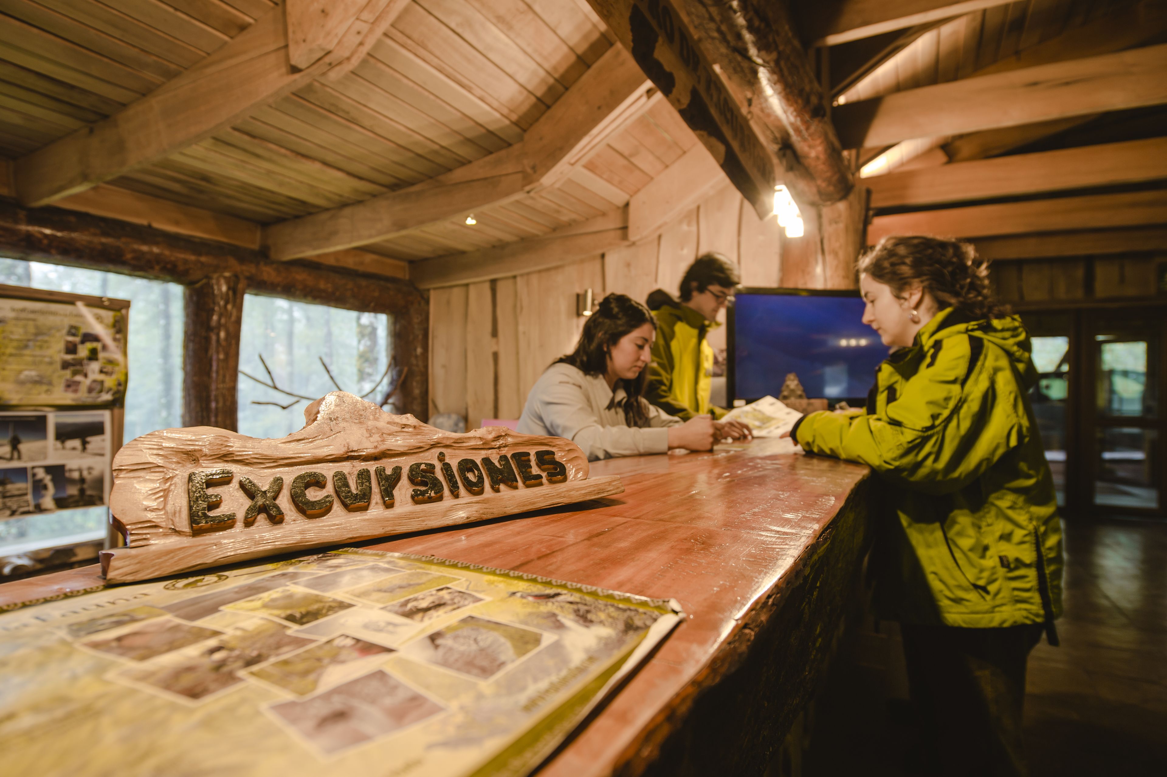 A wooden interior with a reception desk displaying a sign that reads "Excursiones."
