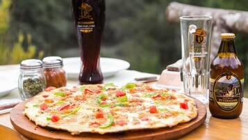Pizza sobre una tabla de madera, con una botella de cerveza y vasos sobre la mesa.
