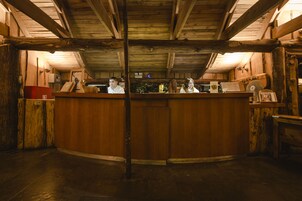 Un mostrador de recepción de madera con dos empleados, techo de madera y un interior rústico.