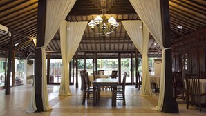 A spacious indoor area with a high ceiling, a chandelier, and a large table surrounded by chairs. - SARE Suites (Jakarta)