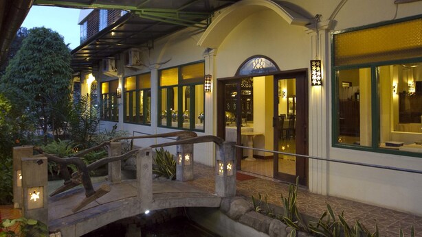 A traditional building with a stone bridge, arched windows, and a well-lit entrance. - SARE Suites (Jakarta)