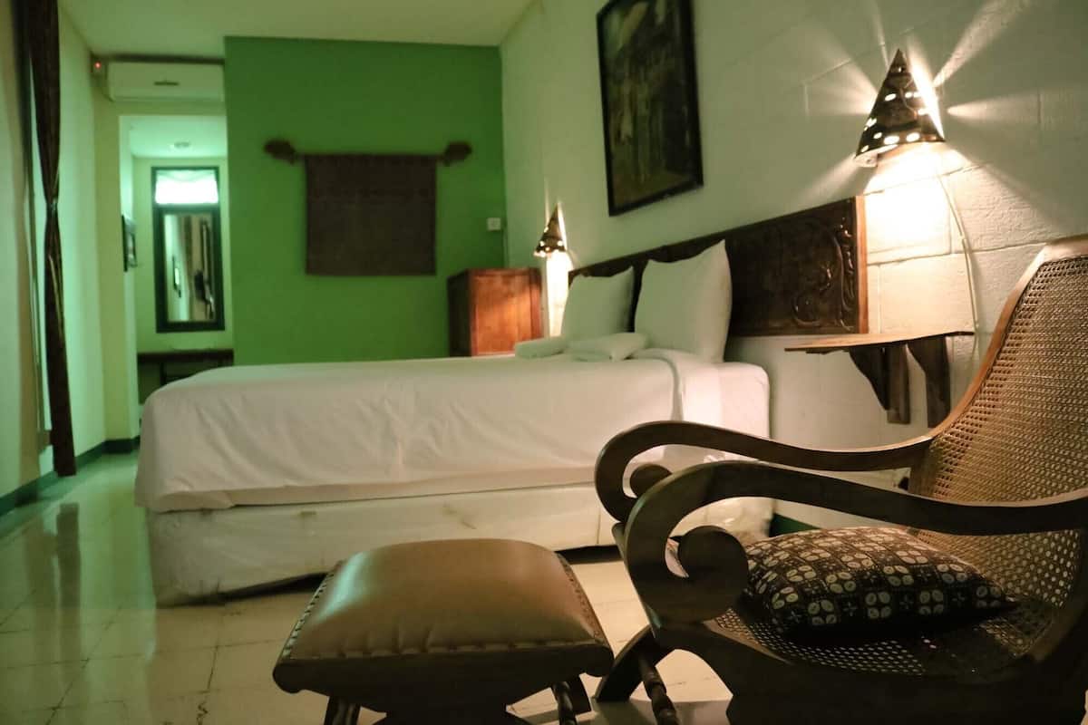 A hotel room with a bed, a chair, and a lamp.