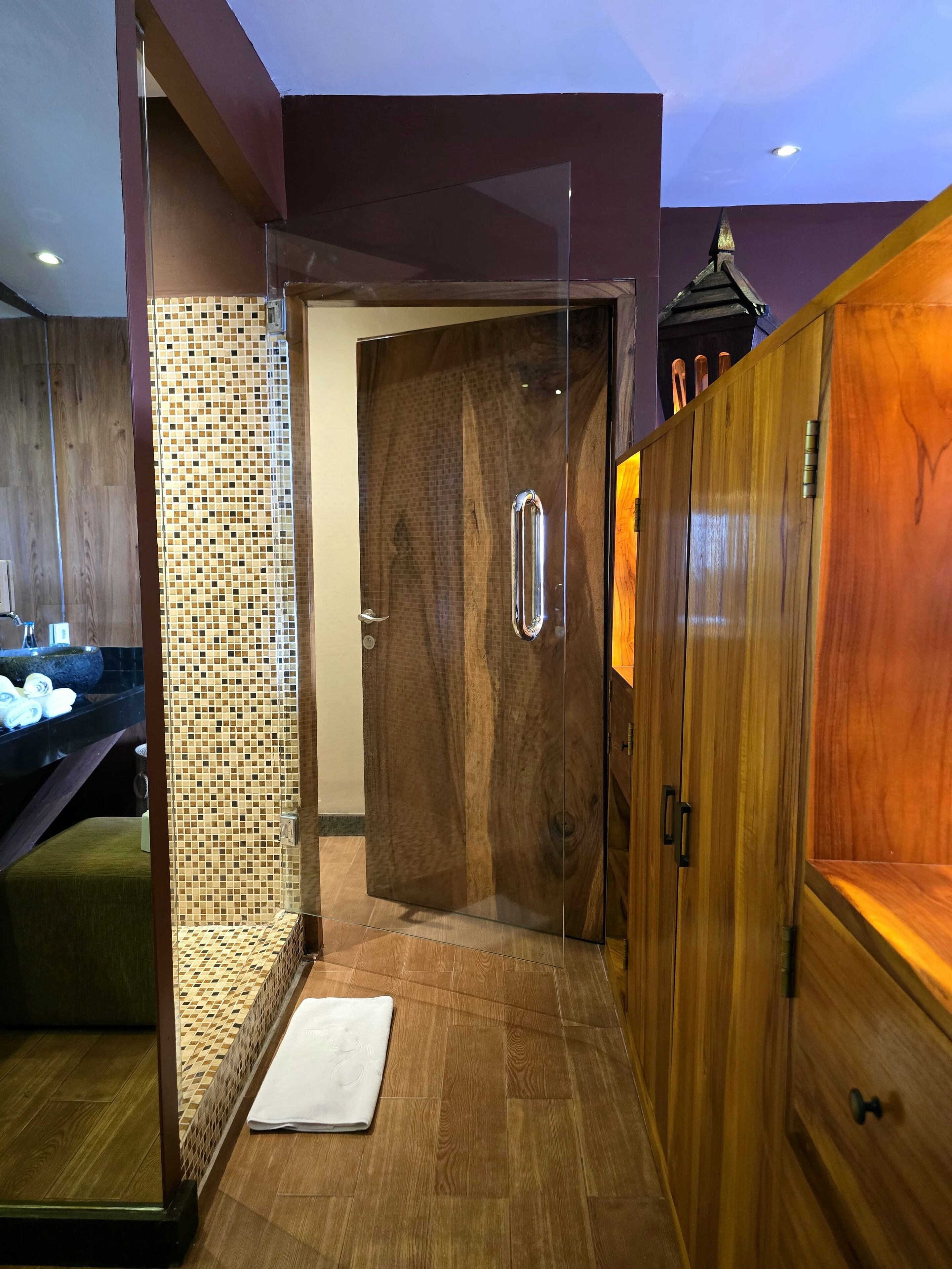 Un baño moderno con piso de madera, cabina de ducha de vidrio y tocador de madera con espejo.