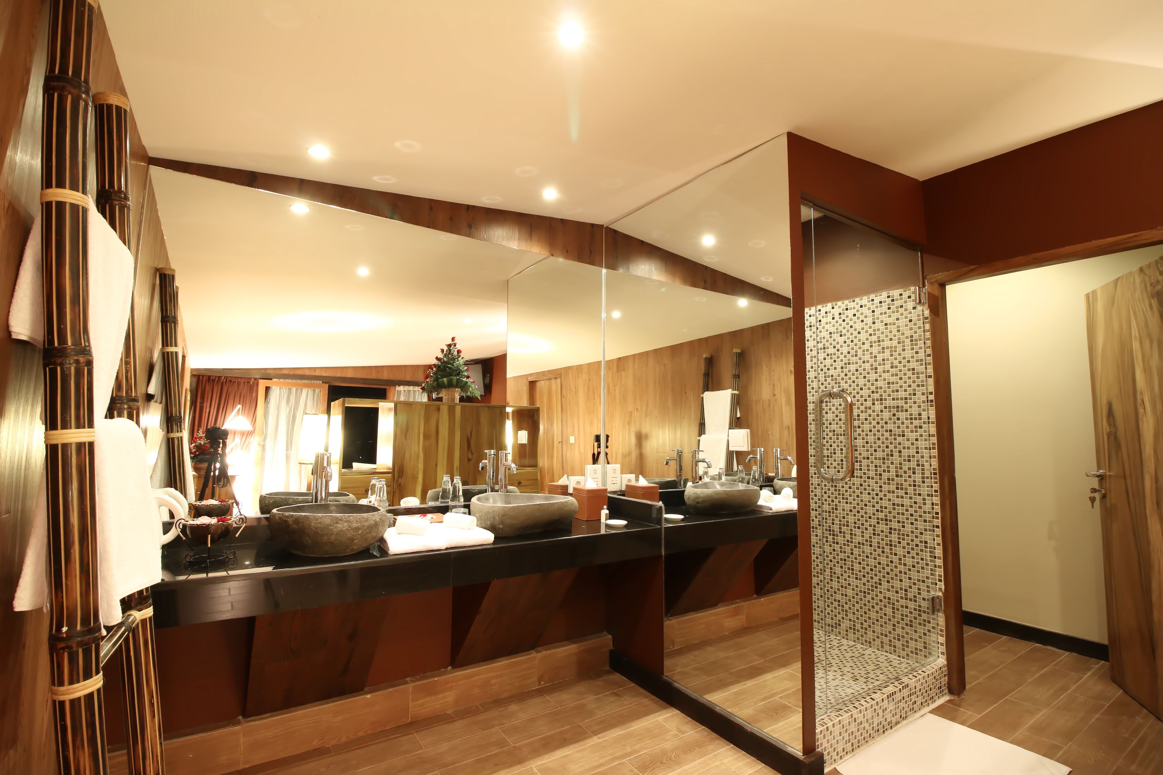 A modern bathroom with a large mirror, wooden vanity, and a glass shower enclosure.