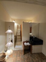 Um banheiro com pia preta, espelho, porta-toalhas e abajur.