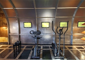Un gimnasio con bicicletas estáticas, elípticas y mancuernas.