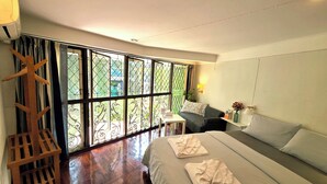 A modern hotel room with a large bed, a small desk, and a view through a large window. - Home16 Hostel 16 (Bangkok)