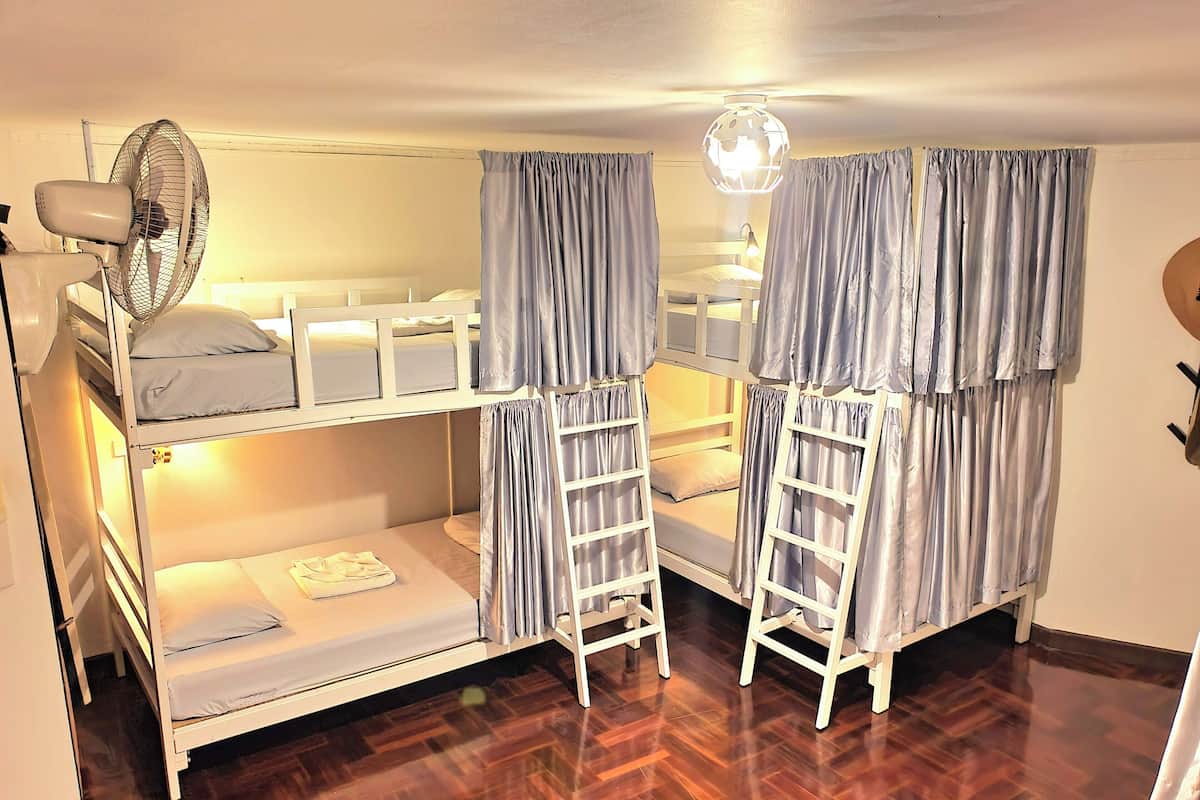 A bunk bed room with a fan, curtains, and a globe light fixture.