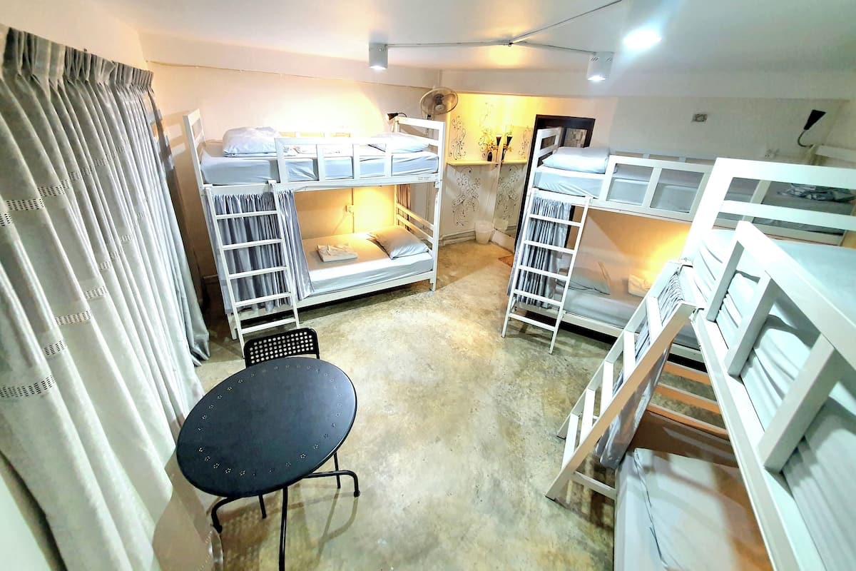 A compact room with bunk beds, a small table, and a ceiling fan.