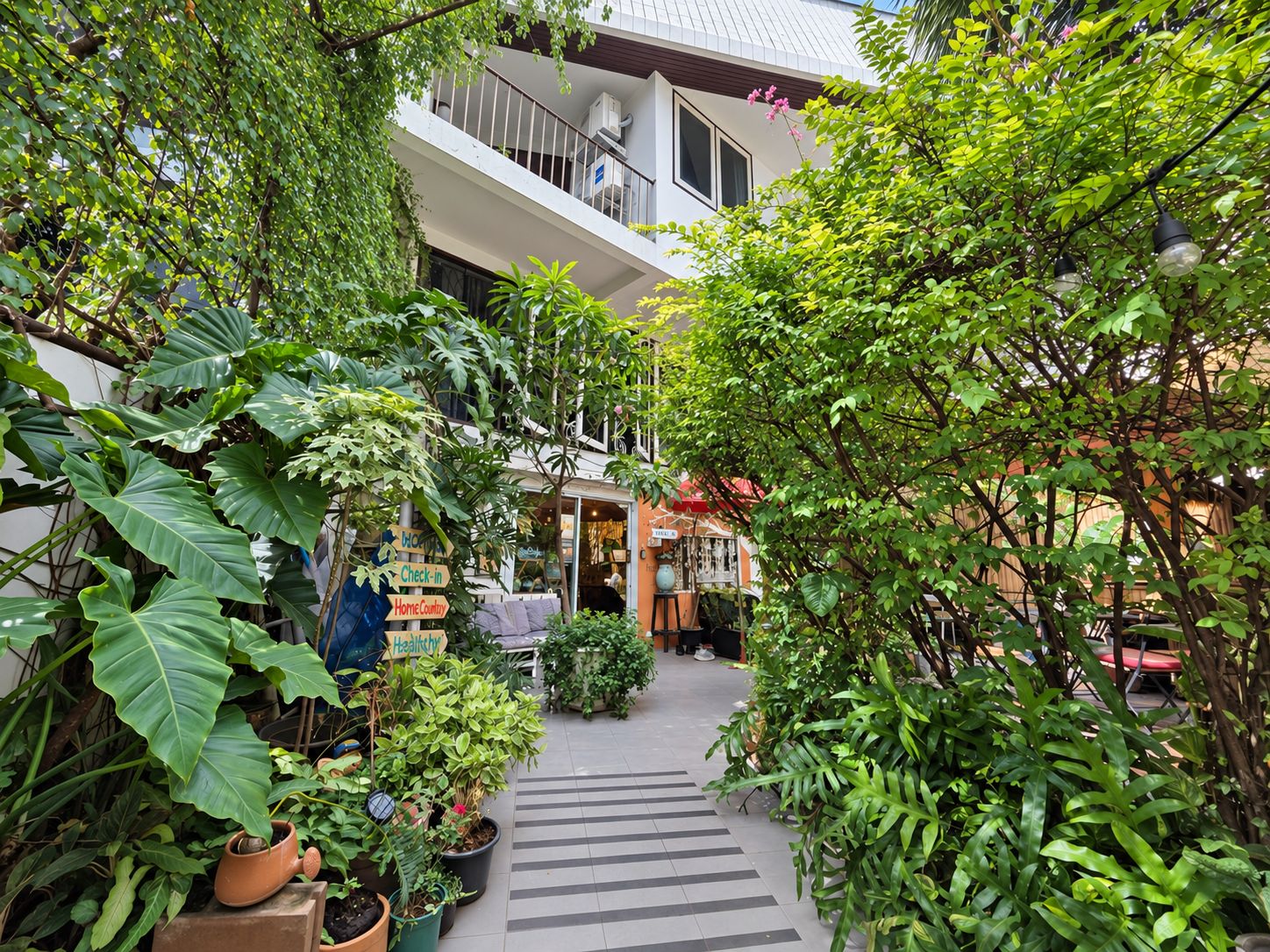 A courtyard with potted plants, a check-in sign, and a building with a balcony.