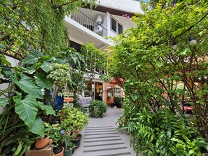 A courtyard with potted plants, a check-in sign, and a building with a balcony.