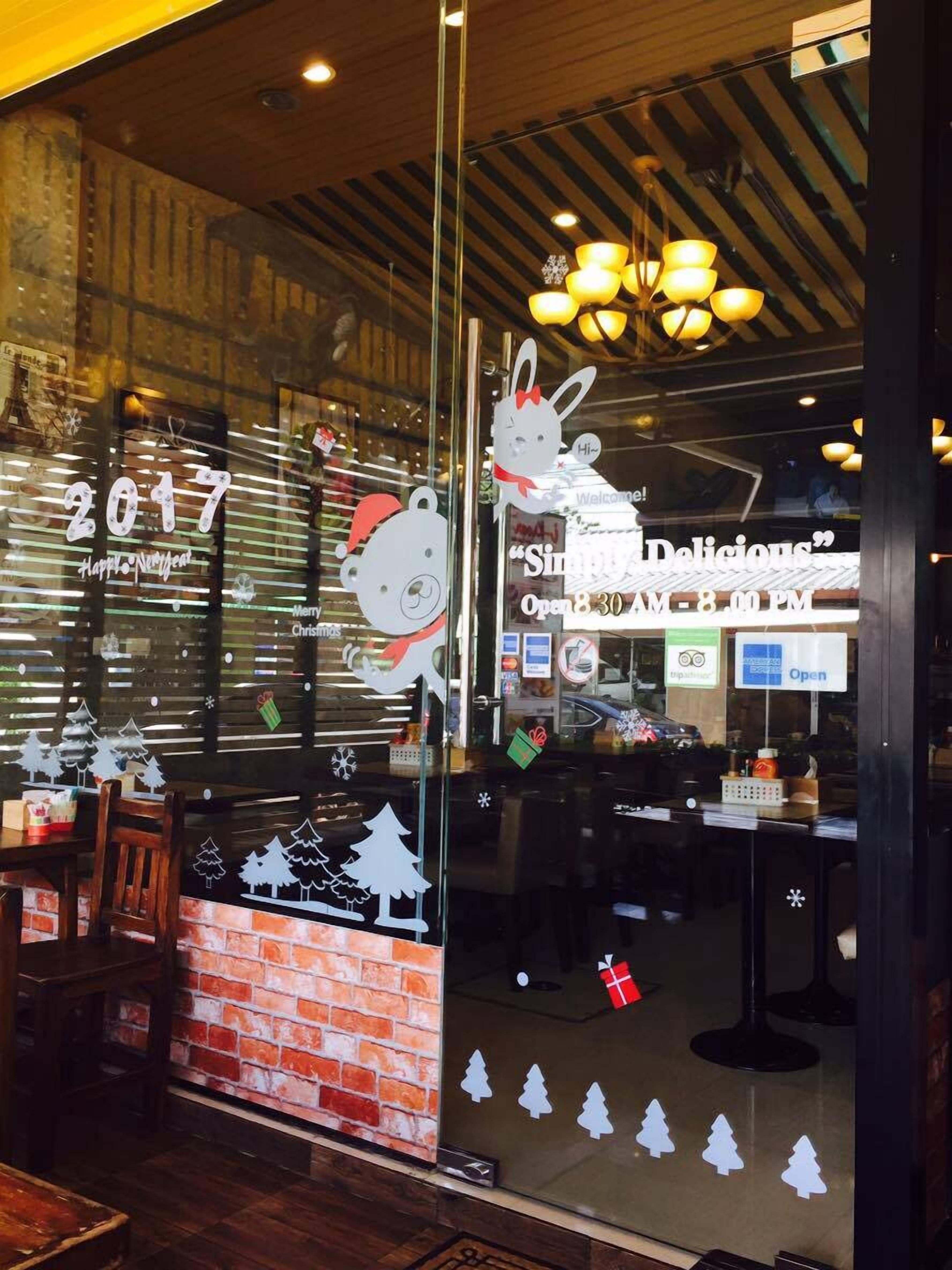 A restaurant with a Christmas theme, including a window display with a cartoon character and trees.