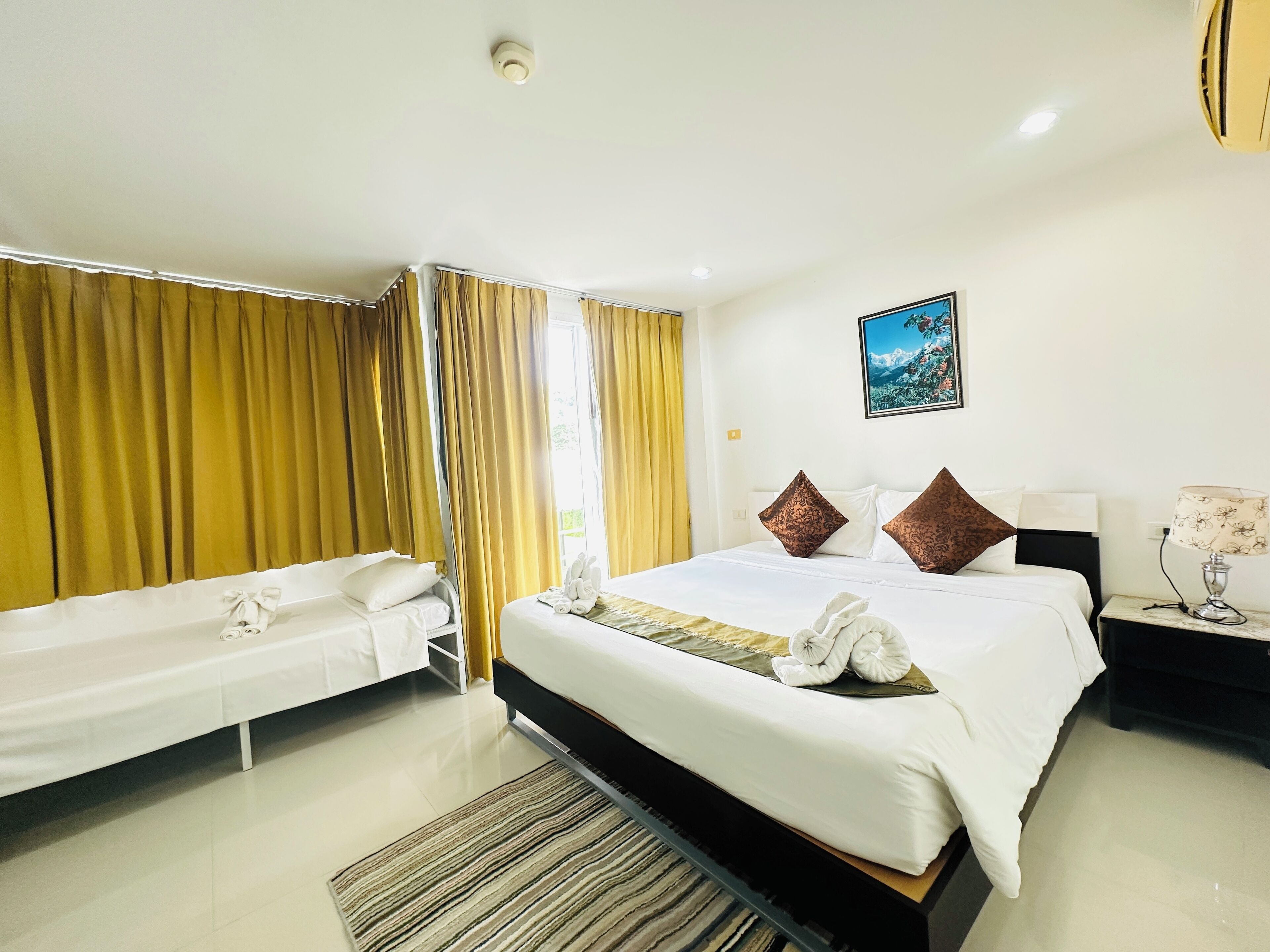 A hotel room with a bed, a sofa, a nightstand, and a bathroom.