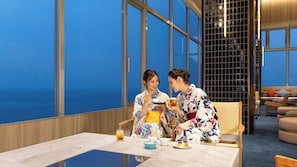 Two individuals seated at a table with a view of the sea through large windows. - TAOYA Atami (Atami)