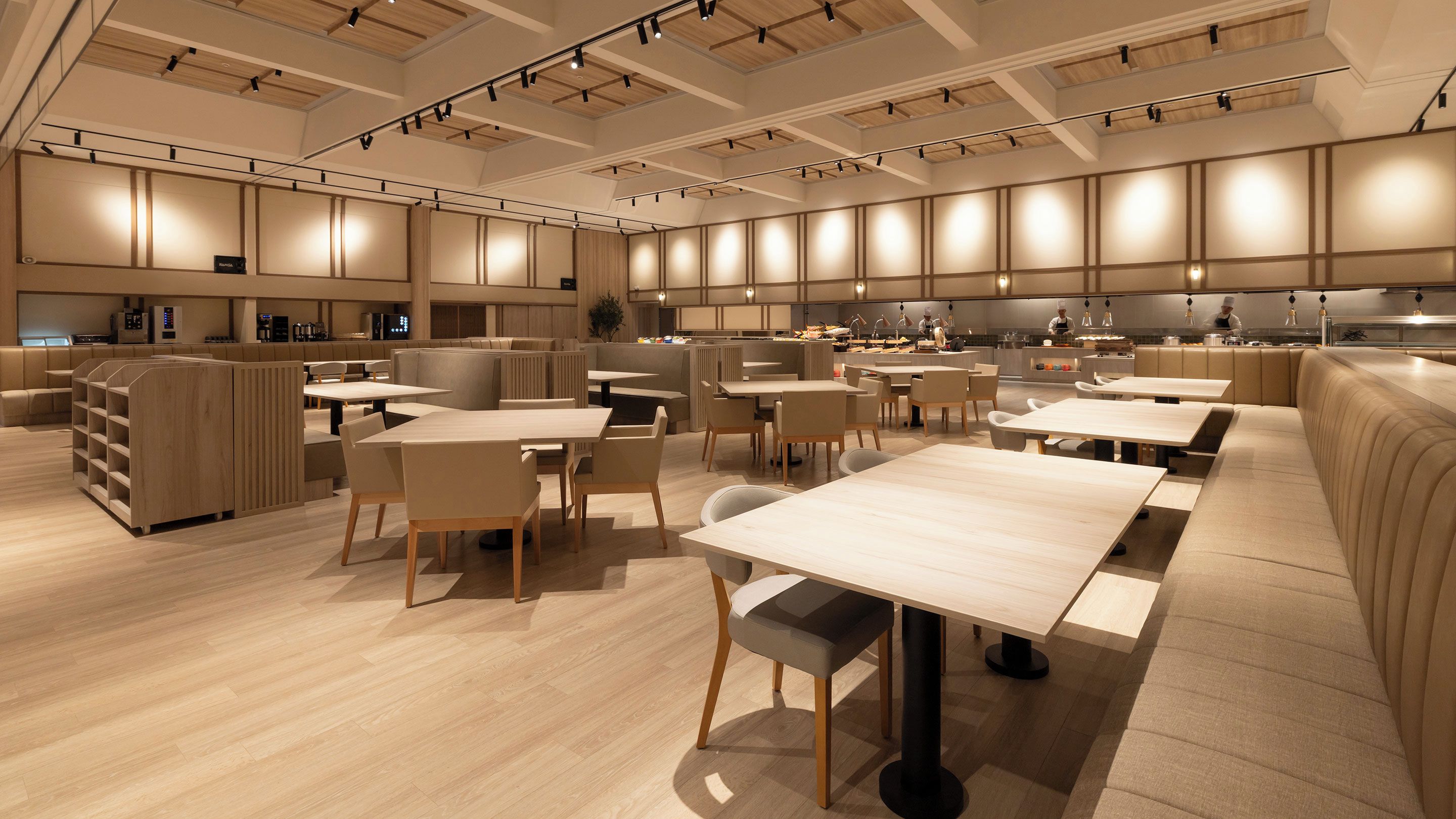 A modern restaurant interior with high tables and booths, a kitchen area, and a bar.