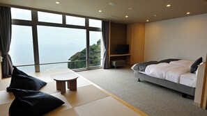 Una habitación de hotel con un ventanal grande, una cama, una mesita y un televisor.