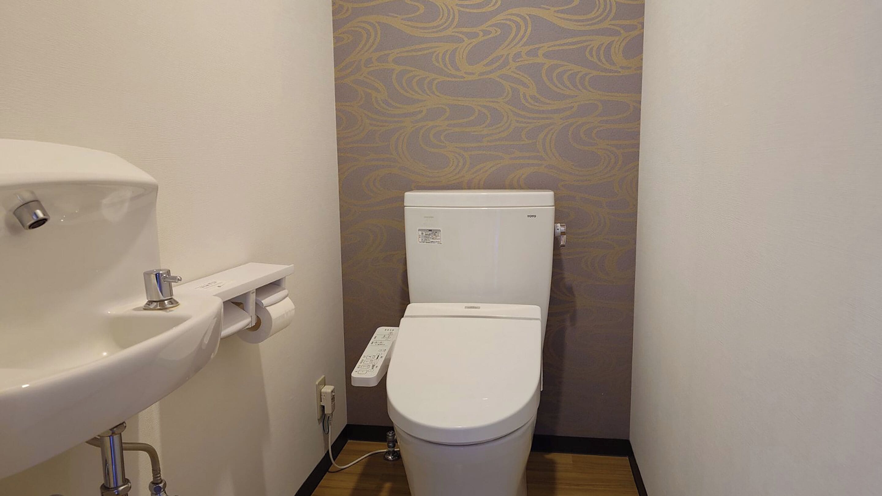 A small bathroom with a toilet, sink, and paper towel dispenser.