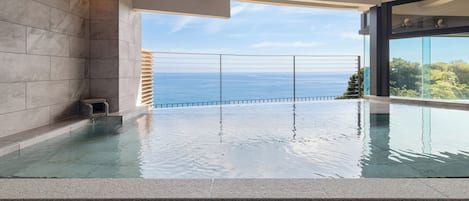Une piscine à débordement offrant une vue imprenable sur l’océan, un design architectural moderne et une barrière en verre.
