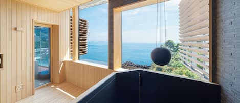 A modern interior with wooden paneling, a black heated floor, and large windows overlooking the sea.