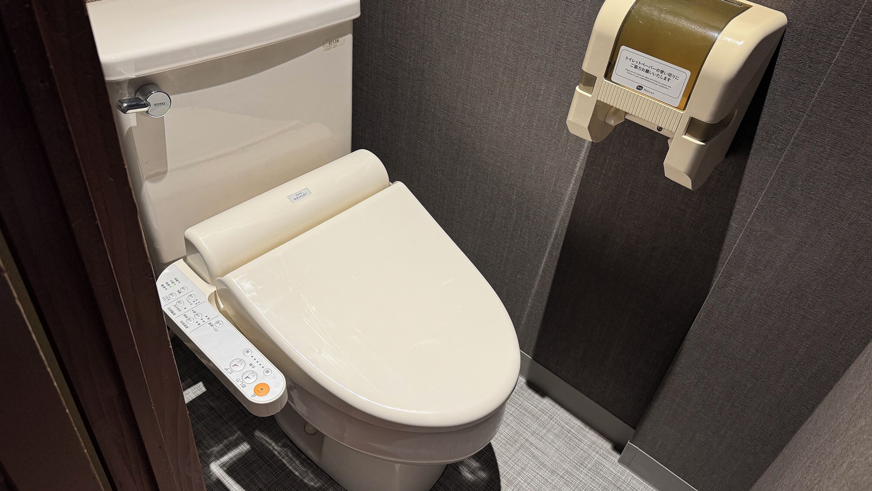 Een moderne toiletruimte met een bedieningspaneel, een toiletpapierautomaat en een wandmodel bidet.
