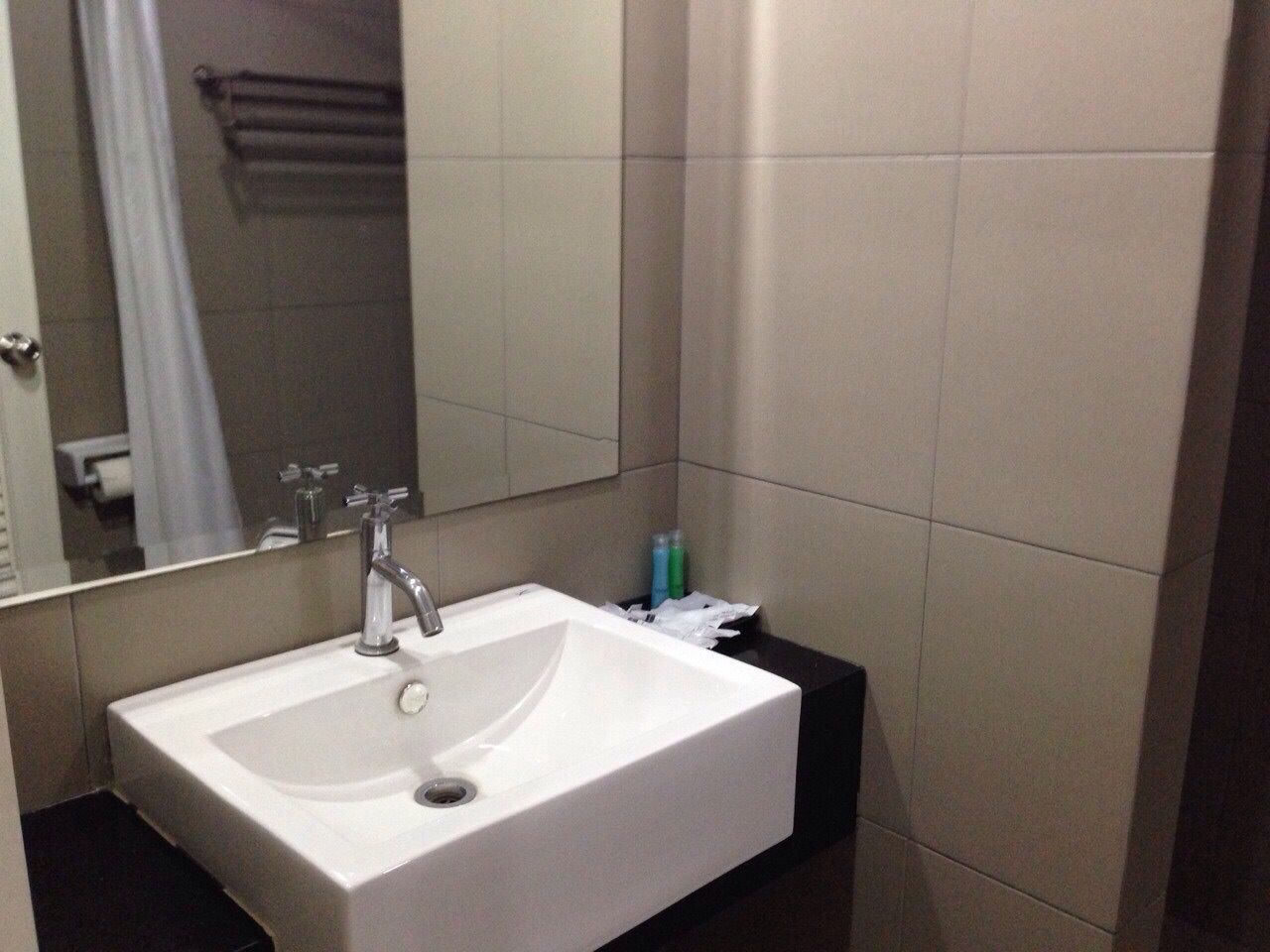 A bathroom with a white sink, a mirror, and a towel rack.