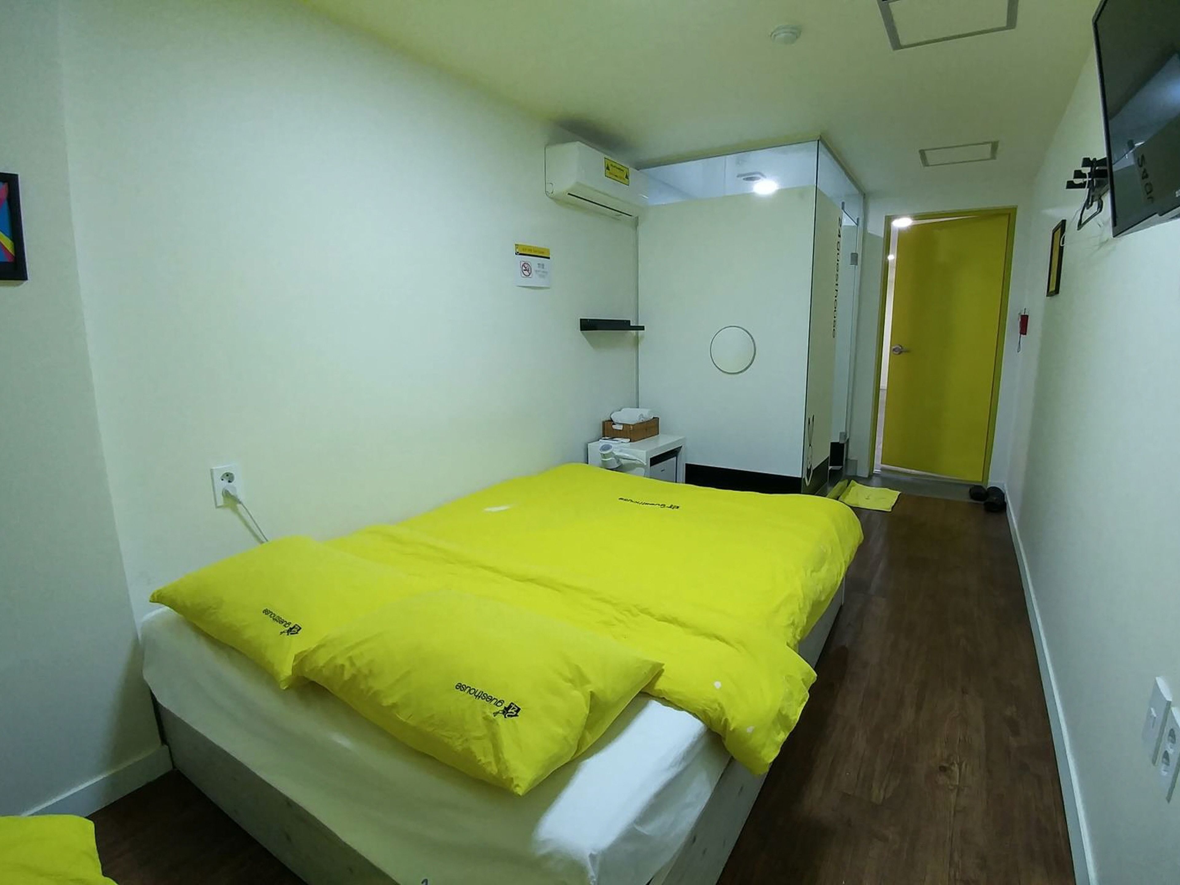 A hotel room with a bed, a bedside table, a chair, a wardrobe, and a door.