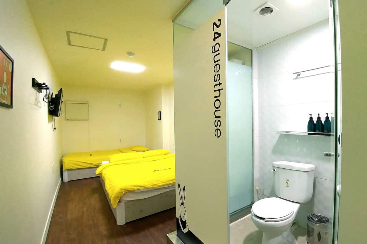 Ein kleines Zimmer mit zwei Betten, einer Toilette und einer Dusche.