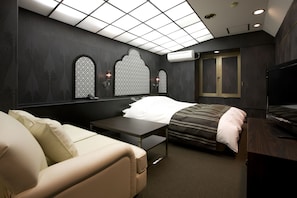 A modern hotel room with a bed, a sofa, a small table, and a TV. - Hotel Jay - Adults only (Osaka)