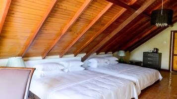 Un dormitorio con techo de madera, una cama con ropa de cama blanca, una mesita de noche y un aparador.