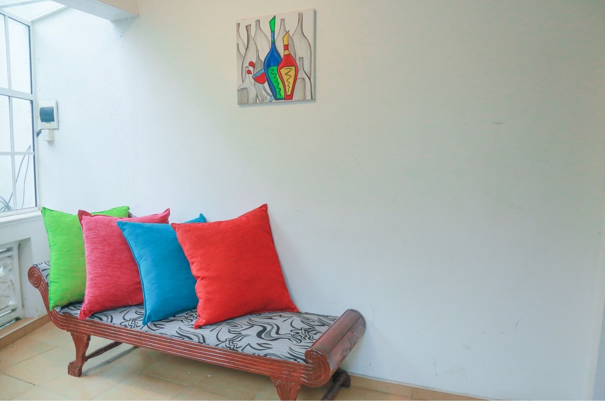 Ein Sofa mit bunten Kissen in einem Zimmer mit weißer Wand und einem Bild.