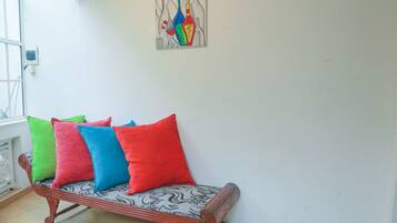 Ein Sofa mit bunten Kissen in einem Zimmer mit weißer Wand und einem Bild.