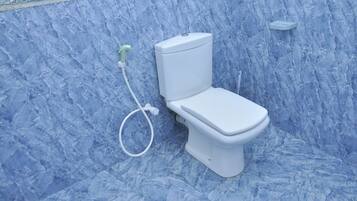A toilet with a bidet attachment in a bathroom with blue marble walls.