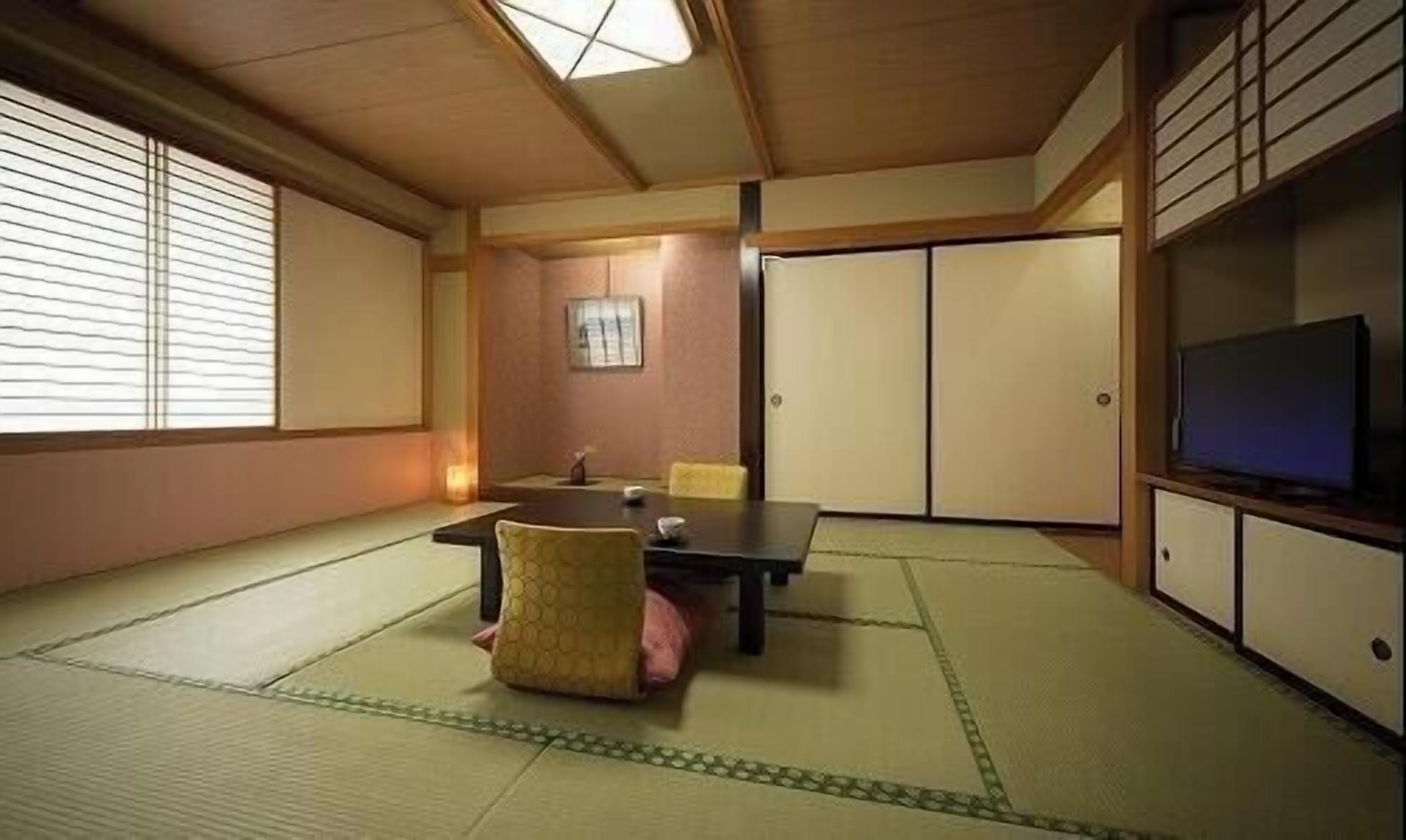 A traditional Japanese room with tatami flooring, a low table, a television, and sliding doors.