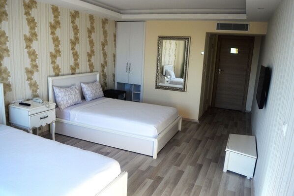 A hotel room with a bed, a nightstand, a dresser, a mirror, and a television.