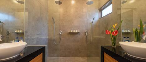 A modern bathroom with two sinks, a glass-enclosed shower area, and a small window.