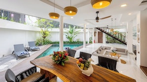 Un interior moderno con piscina, zona de estar y una escalera que lleva a un nivel superior.