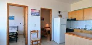 Une cuisine compacte avec des meubles en bois, un réfrigérateur blanc et un petit coin repas comprenant une chaise et une table.