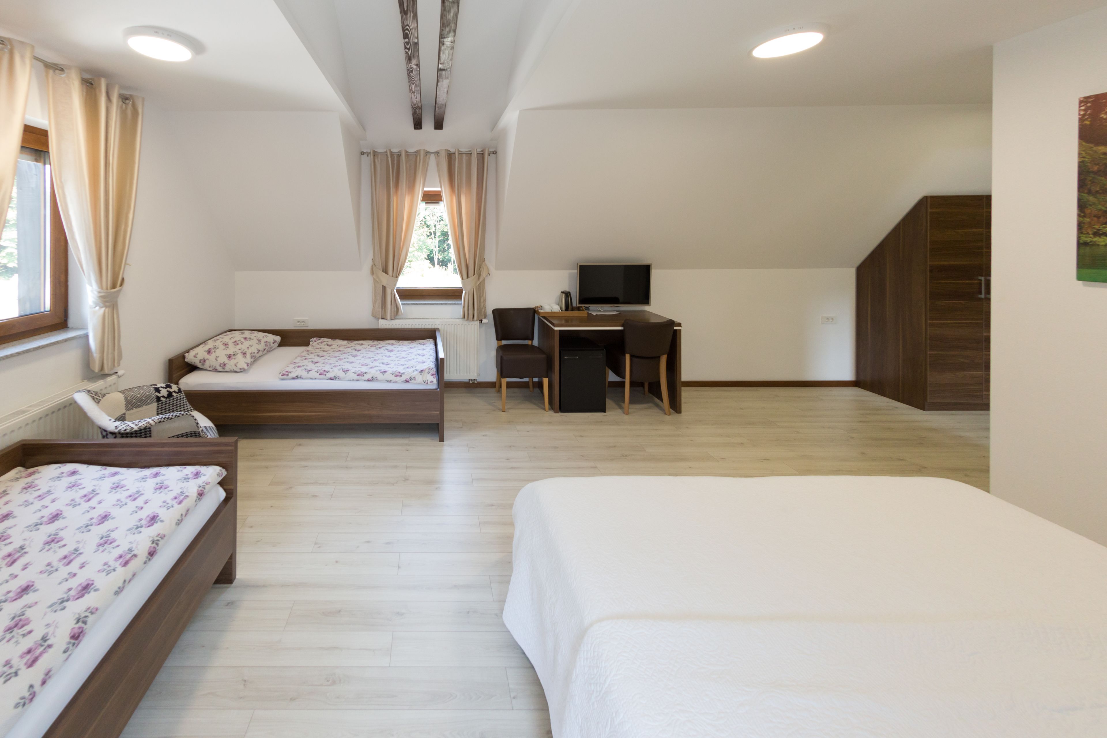 A room with two beds, a desk, and a television.