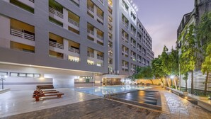 Un hôtel moderne à plusieurs étages, doté d’une piscine extérieure et de balcons bien éclairés.