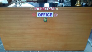A wooden reception desk with a sign indicating an office and internet cafe.