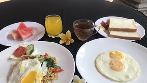 A table with breakfast items including eggs, noodles, and fruit.