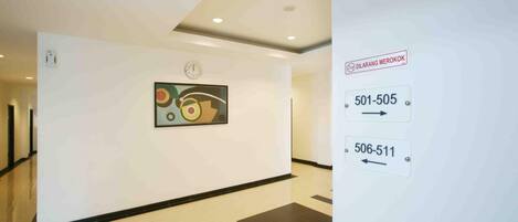 A hallway with a clock, a painting, and directional signs for rooms 501-505 and 506-511.