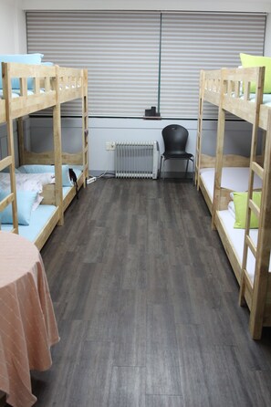 A room with two bunk beds, a radiator, a chair, and a table.