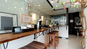 Um café moderno com balcão de madeira, banquetas e uma máquina de café.