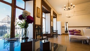 A spacious living room with a large window, wooden flooring, a white sofa, and a chandelier. - Holidays2Malaga Comfort Apartments (Málaga)